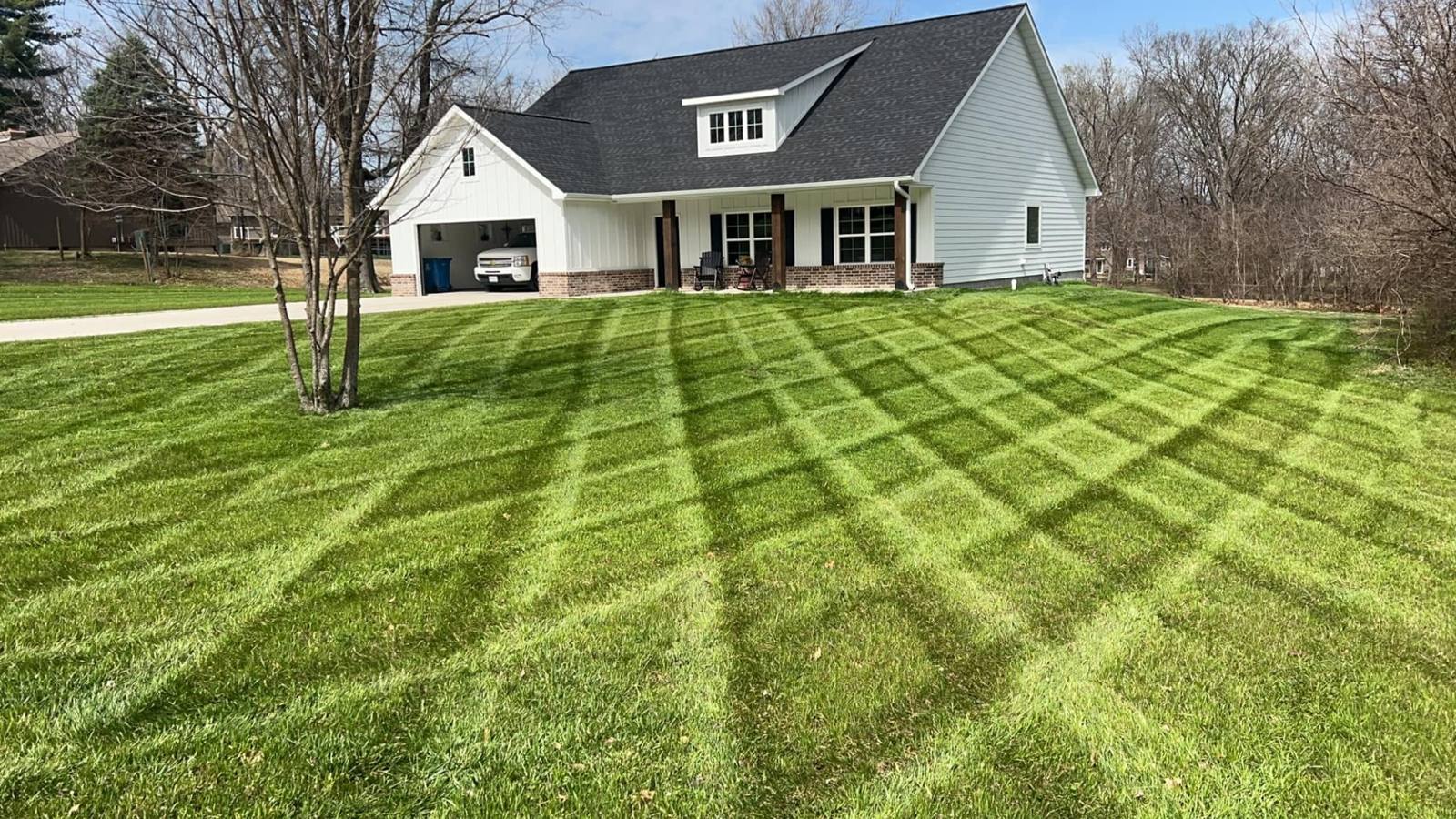 Lawn mowed in a crisp crosshatch pattern in front of a white farmhouse