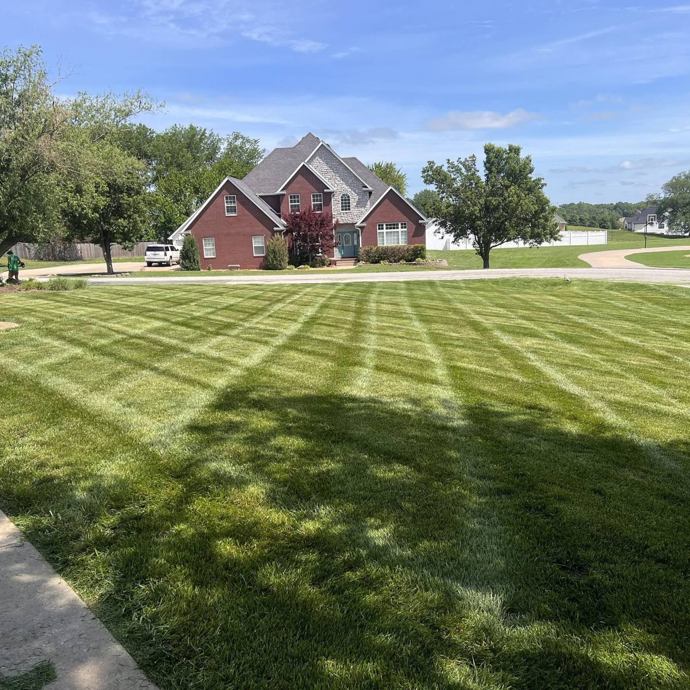 Freshly striped lawn across from a brick home