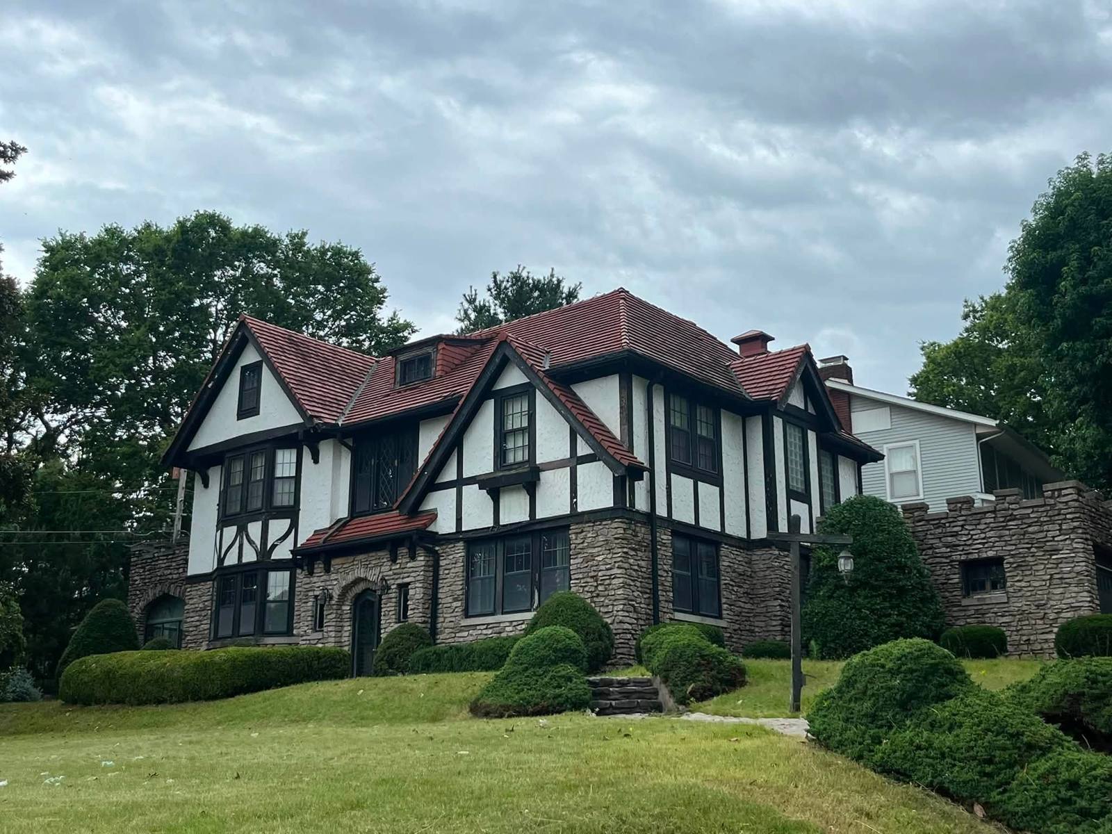 Same Tudor home with mowed lawn and neatly shaped shrubs