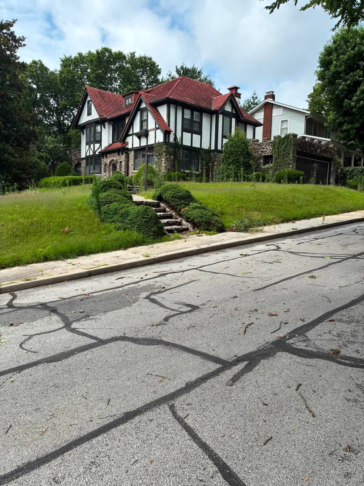 Tudor home with overgrown lawn, shrubs and ivy before cleanup